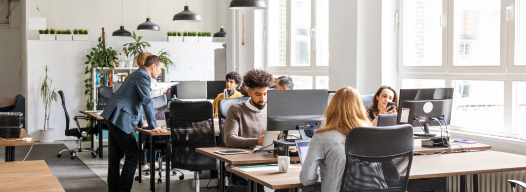 Employees engaged at desks in a well-lit office, emphasizing teamwork while addressing issues related to revenue leak.